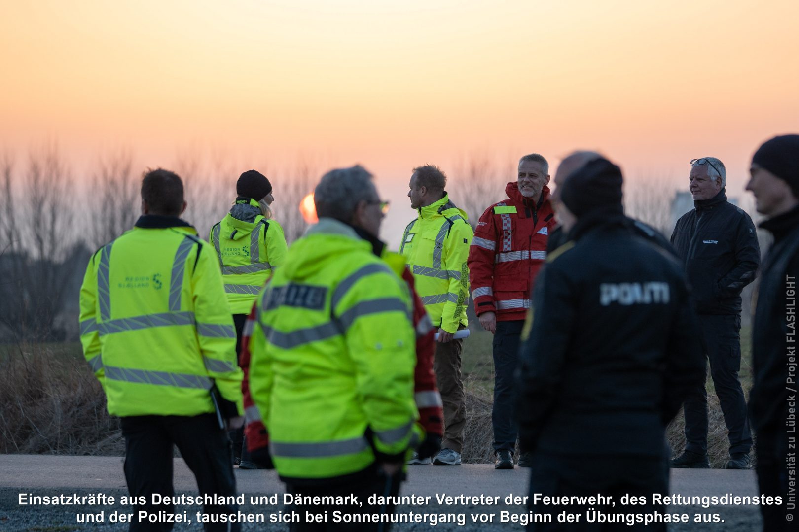 Einsatzkräfte aus Deutschland und Dänemark tauschen sich bei Sonnenuntergang vor Beginn der Übungsphase aus. 